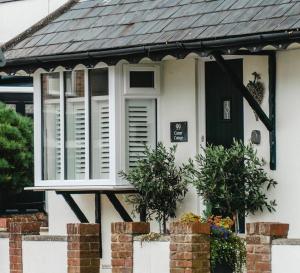a white house with a window and a black door at Corner Cottage - character, charm, great location. in Ringwood