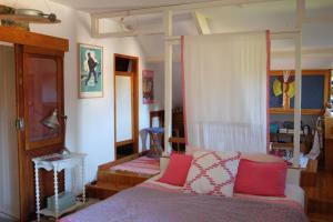1 dormitorio con 1 cama con almohadas rojas y blancas en Le clos du Ru, en Presnoy