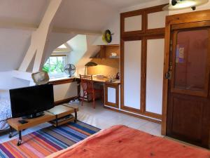 a living room with a bed and a desk with a tv at Le clos du Ru in Presnoy