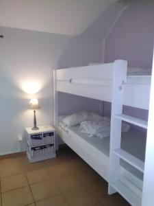 ein weißes Etagenbett in einem Zimmer mit einer Lampe in der Unterkunft Seeperle 3, Wunderschöne Maisonett Ferienwohnung unter Reet! in Sankt Peter-Ording