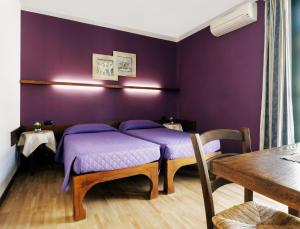 two beds in a room with purple walls at Il Fiordaliso Foresteria in Busto Arsizio