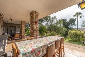 a table and chairs on a patio with a stone pillar at Tygerfontein Safari Villa in Amakhala Game Reserve