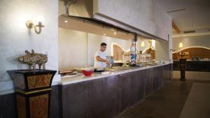 Dois homens estão a preparar comida numa cozinha de restaurante. em Amarina Jannah Resort & Aqua Park em Baía de Coraya