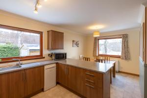 a kitchen with wooden cabinets and a large window at Aonach in Kingussie