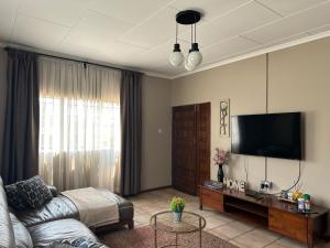 ein Wohnzimmer mit einem Sofa und einem Flachbild-TV in der Unterkunft Serene 3 bedroom house in Olympia, Lusaka in Lusaka