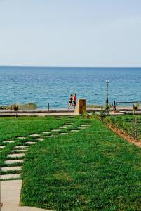 dos personas caminando por un camino junto al agua en Sea View Beachfront Villa Maria, en Gouves