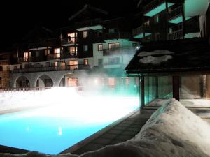 ein nachts beleuchteter Pool mit Schnee in der Unterkunft Rustic apartment on the slopes in cozy Val Cenis in Lanslebourg-Mont-Cenis
