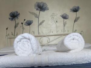 - une paire de serviettes sur un lit avec des fleurs sur le mur dans l'établissement Testaccio appartamento per gli amanti di un caffè in terrazzo, à Rome