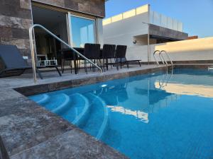 a swimming pool with chairs next to a house at Fee4Me 2 Bedroom House with Private Pool and Rooftop Terrace in Alicante