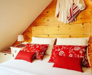 1 dormitorio con almohadas rojas y blancas en una cama en Csárdás Salaš, en Dobrovnik