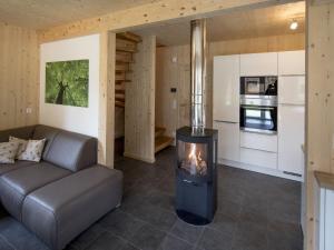 a fireplace in a living room with a couch and a kitchen at Wooden Chalet in Sankt Georgen ob Murau with Sauna in Sankt Lorenzen ob Murau