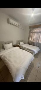 two beds in a room with white sheets at شاطئ البحر Durrah Al Arus in Durat Alarous