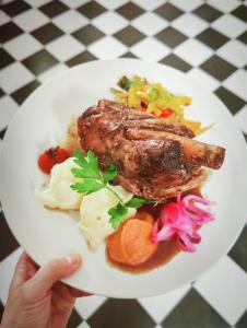 une personne détenant une plaque de nourriture avec de la viande et des légumes dans l'établissement Hôtel Restaurant U Castellu Vizzavona, à Vizzavona