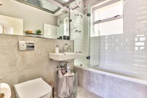 a bathroom with a sink and a toilet and a tub at Trendy 1 bedroom flat in the heart of Green Point in Cape Town