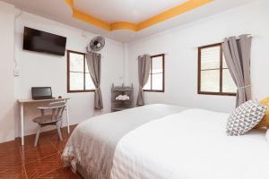 Schlafzimmer mit einem Bett, einem Schreibtisch und Fenstern in der Unterkunft Garden Home 4 in Haad Yao