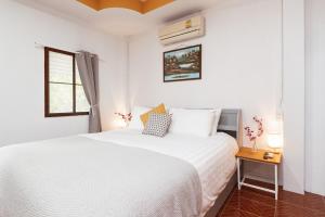 a bedroom with a white bed and a window at Garden Home 4 in Haad Yao