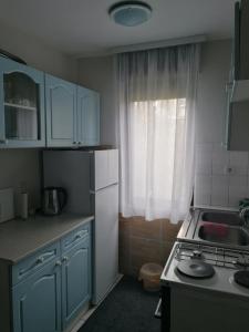 kuchnia z niebieskimi szafkami, umywalką i oknem w obiekcie Kuća za odmor Dunavski raj w mieście Batina