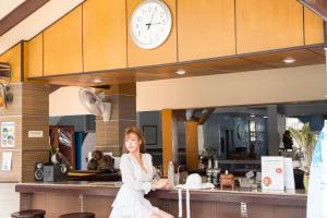 a woman sitting in front of a counter with a clock at S Lodge Pattaya formally Sabai Lodge in Pattaya