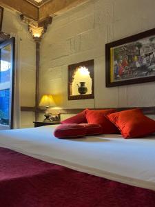 a bedroom with a large bed with red pillows at Raj Mandir Boutique Home Stay in Jodhpur