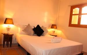 una camera con due letti con lenzuola bianche e due lampade di Asunfou : Appartement d'apaisement a Mirleft