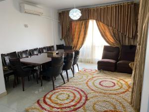 comedor con mesa, sillas y alfombra en شقة فندقية بإطلالة خيالية مكيفة بالكامل للايجار في مدينتي-Madīnat, en Madinaty