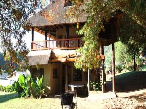 una casa con balcón y una mesa frente a ella en Emahlathini Guest Farm, en Piet Retief