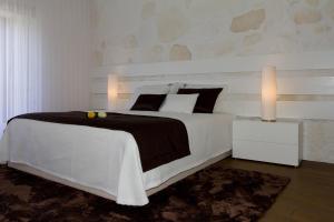 a white bedroom with a large bed with two lights at Cantinho do Cantador in Riba de Mouro