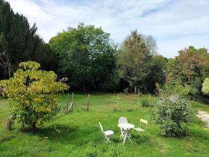 una mesa y sillas en un campo con árboles en Logement entier pour 6 personnes en Saint-Maixent-lʼÉcole