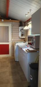 cocina con electrodomésticos blancos y puerta roja en Zizania, en Noord-Sleen