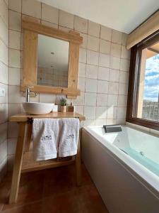 ein Badezimmer mit einem Waschbecken, einer Badewanne und einem Spiegel in der Unterkunft Vistas Del Maestrazgo apartamentos Rurales in Allepuz