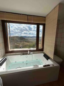 eine Badewanne im Bad mit einem großen Fenster in der Unterkunft Vistas Del Maestrazgo apartamentos Rurales in Allepuz