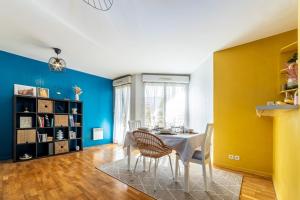 a dining room with blue and yellow walls and a table and chairs at Appartement near Disneyland Paris, 2 parking in Torcy