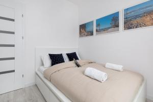 a white bedroom with a large bed with two pillows at Apartament Bursztynowa Przystań in Dziwnówek