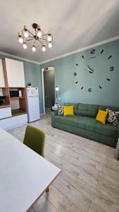 a living room with a green couch and a clock on the wall at Новый ЖК в самом центре города in Almaty