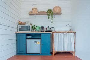 a kitchen with a blue refrigerator and a microwave at Vawa Guesthouse in Kanchanaburi