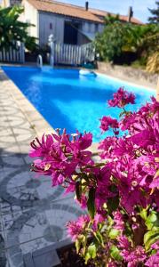 a blue swimming pool with purple flowers in front of it at Les Bichettes in Mortagne-sur-Sèvre