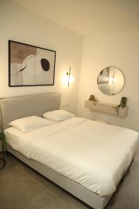 1 dormitorio con 1 cama blanca grande y espejo en חדרי בוטיק B.Y, en Beit She'an