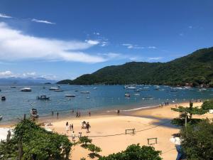 eine Gruppe von Menschen am Strand mit Booten im Wasser in der Unterkunft Suites Abraão Beach in Abraão