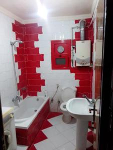 uma casa de banho vermelha e branca com um WC e um lavatório em شقة مفروشة no Cairo