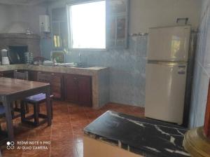 eine Küche mit einem Kühlschrank und einem Tisch darin in der Unterkunft Villa avec piscine in Essaouira
