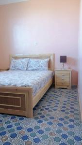 een slaapkamer met een bed en een nachtkastje met een lamp bij Villa avec piscine in Essaouira