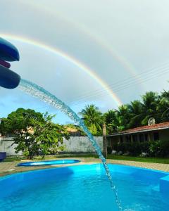 a rainbow in the sky over a swimming pool with at Pousada Moryah in Paripueira
