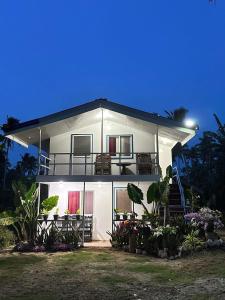 a white house with a balcony on top of it at Bayay ni Nanay Bed & Breakfast in Magpupungko Beach Road in Pilar