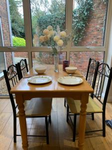 uma mesa de madeira com quatro cadeiras e um vaso de flores em Guest suite Annex private room em Saint Ives