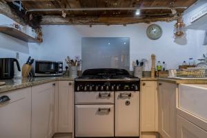 a kitchen with a stove and a counter top at Lantau Cottage: Historic Elizabethan house very close to the beach in Looe