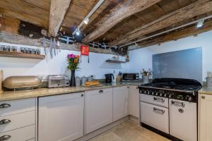 a kitchen with white cabinets and a stove top oven at Lantau Cottage: Historic Elizabethan house very close to the beach in Looe