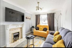 een woonkamer met een bank en een open haard bij Come & unwind in Charming 5 Bed House in Blackburn in Blackburn