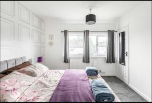 a bedroom with a bed with a purple blanket on it at Come & unwind in Charming 5 Bed House in Blackburn in Blackburn