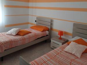 1 dormitorio con 2 camas y mesa con lámpara en CASA T.U.A., en Sale Marasino