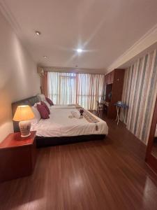 a bedroom with a large bed and a lamp on a wooden floor at Riverbank suites unit 405 in Kuching